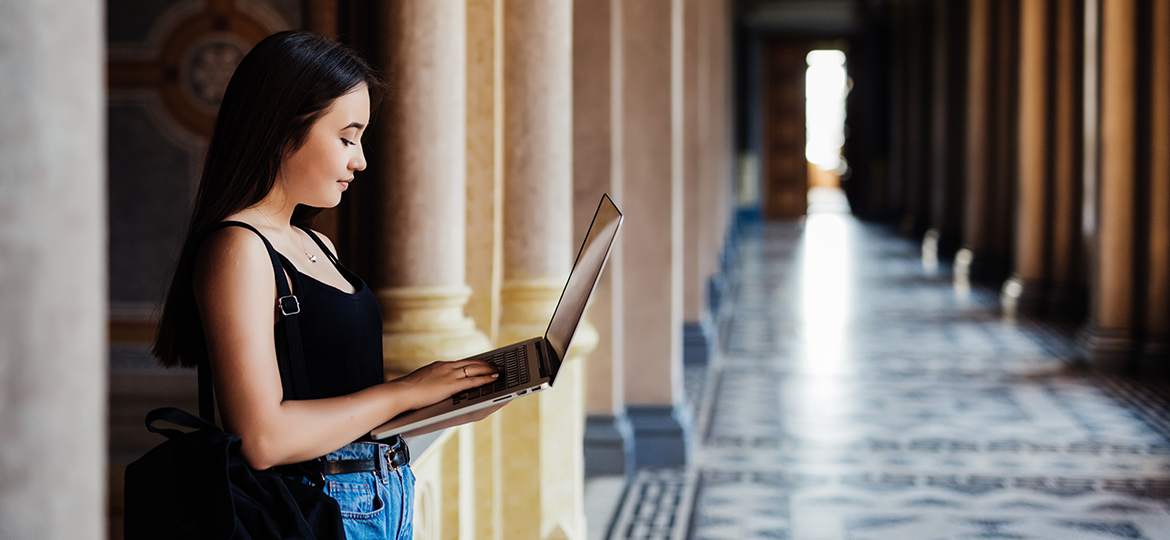 chica trabajando en su notebook desde el pasillo de una arquitectura de Italia